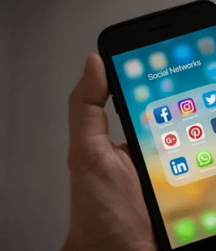 Hand holding smartphone with social media apps.