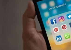 Hand holding smartphone with social media apps.